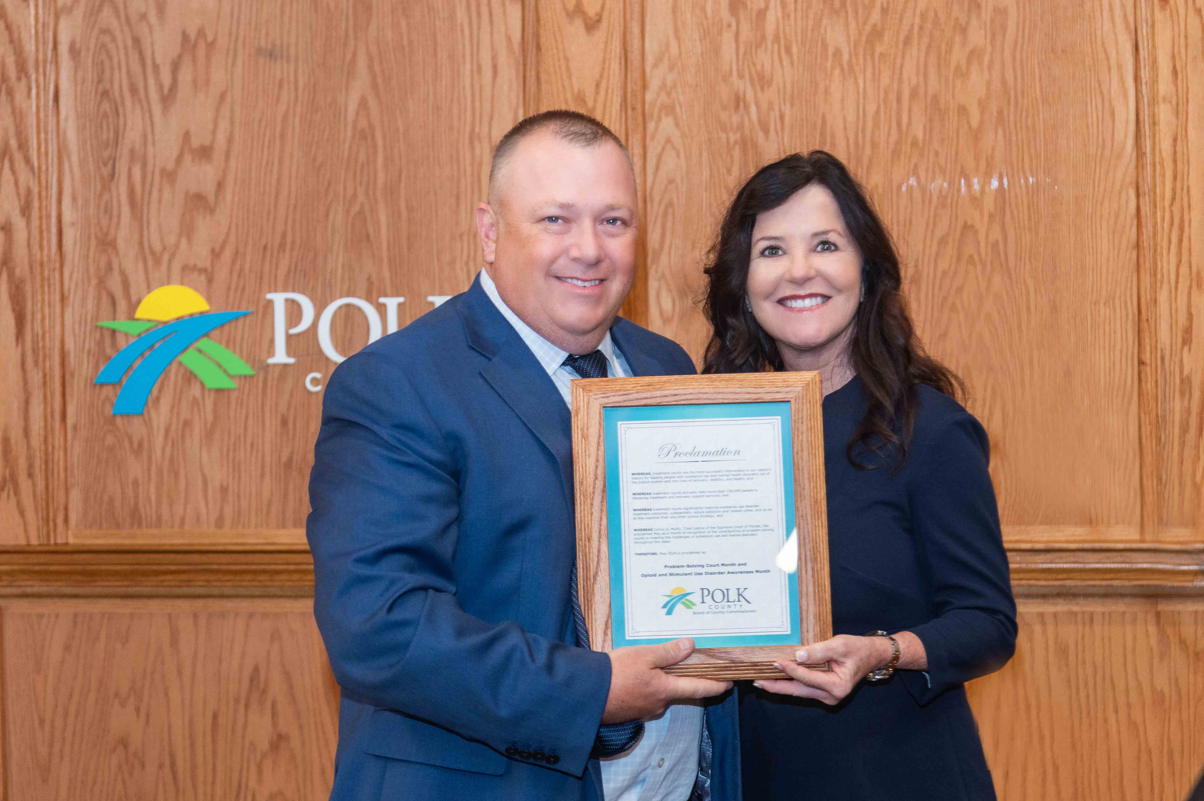 Circuit Judge Susan L. Barber holding Proclamation declaring May 2024 PSC and Opioid and Substance Abuse Awareness Month. On her right is Polk County Attorney Randy Mink.